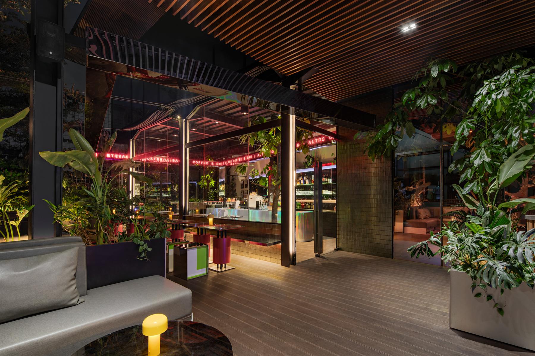 ALTRS terrace at night, red neon signage glowing through the mirrored ceiling