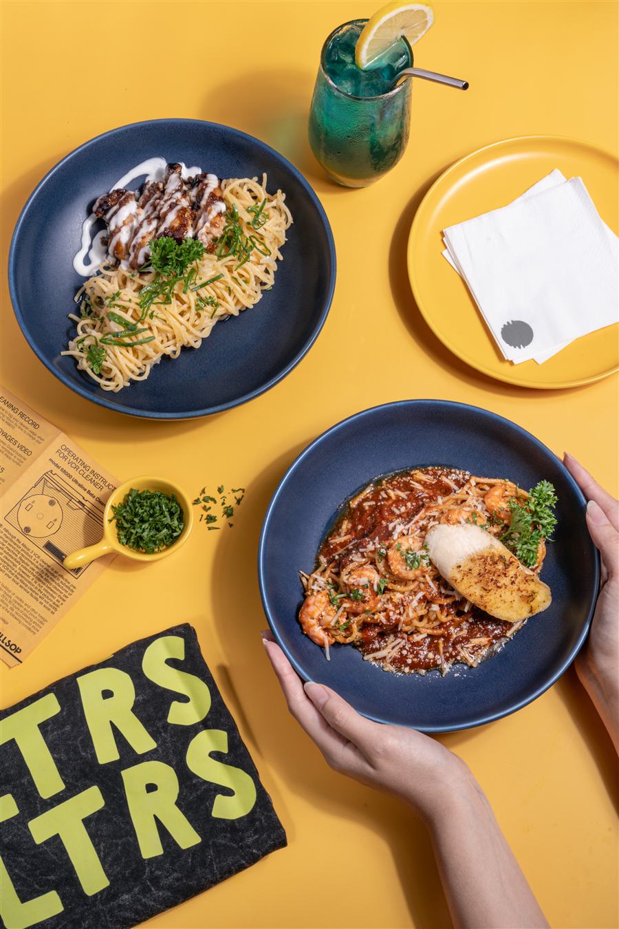 Spaghetti teriyaki and fettucine prawn pomodorini plated, with a blue oceanarei mocktail